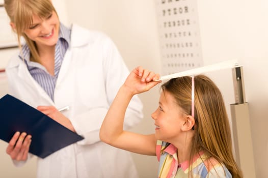 Pediatrician measure height of young girl at medical office