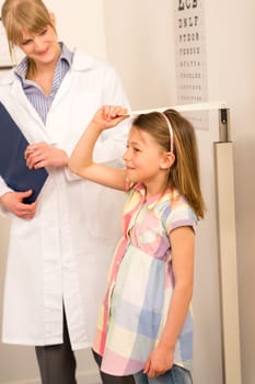 Pediatrician measure height of young girl at medical office