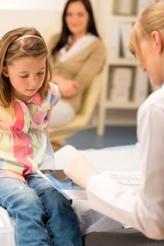 Little girl sitting at medical office pediatrician looking at document