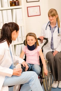 Little injured girl on wheelchair with doctors at medical office