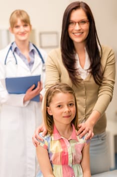 Portrait of little girl with mother and pediatrician in background
