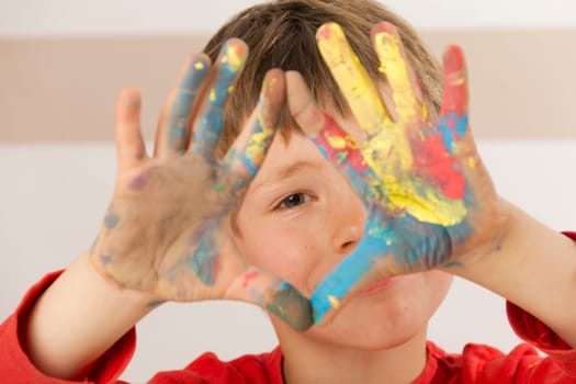 Boy paints with finger paints and shows his painted hands