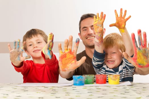 Father painting with his children with finger paint