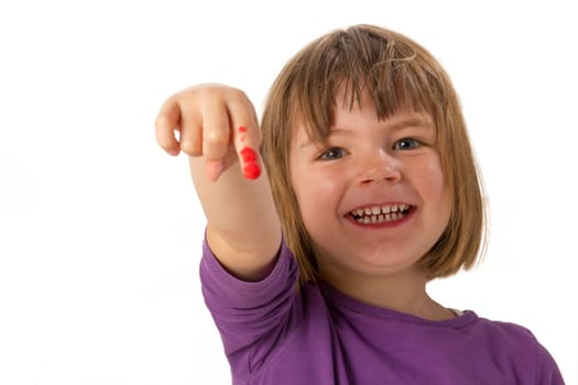 Girl paints with finger paints and shows her red painted finger