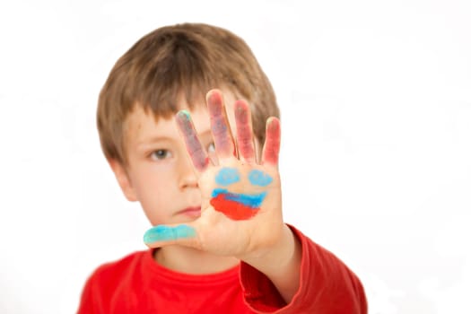 Boy paints a face on his hand with finger paints