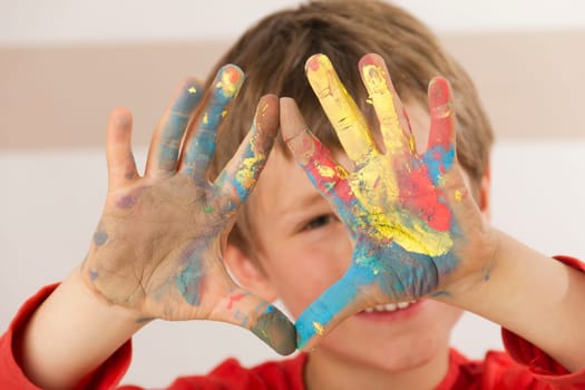 Boy paints with finger paints and shows his painted hands