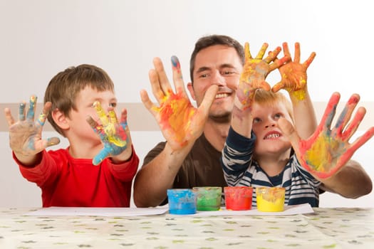 Father painting with his children with finger paint