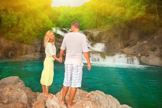 Couple near waterfall at sunrise time