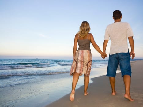 Young couple walking near the ocean on sunset time