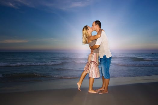 Young couple kissing near the ocean on sunset time