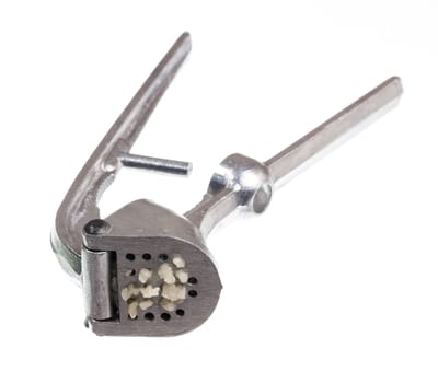 Garlic press and garlic isolated against white in macro shot