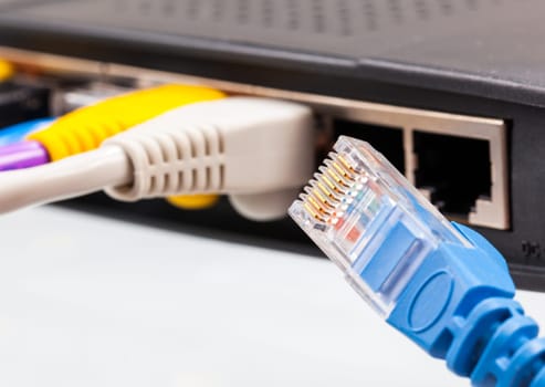 Macro shot of plugs on cat5e cables of many colors isolated against white background plugged into router