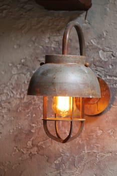 A vintage-style metal lamp illuminates a textured wall, creating warm ambiance.