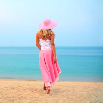 Woman walking near the ocean in pink clothes