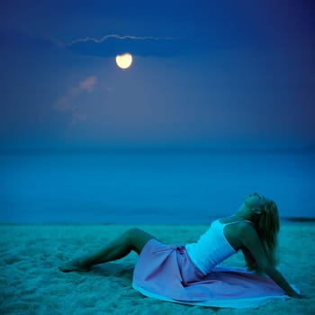Young beautiful woman posing on the beach at night time