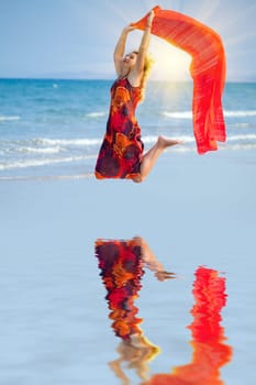 Woman jumping with red sarong at sunset tine