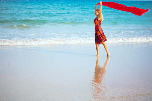 Beautiful woman walking near the ocean with red sarong