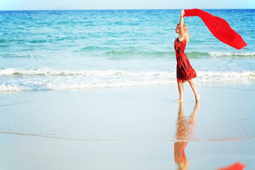 Beautiful woman walking near the ocean with red sarong