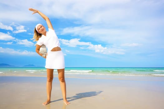 Young woman doing morning exercises close to the ocean