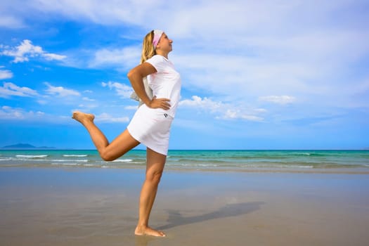 Young woman doing morning exercises close to the ocean