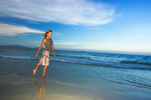 Young woman walking near ocean on sunset time