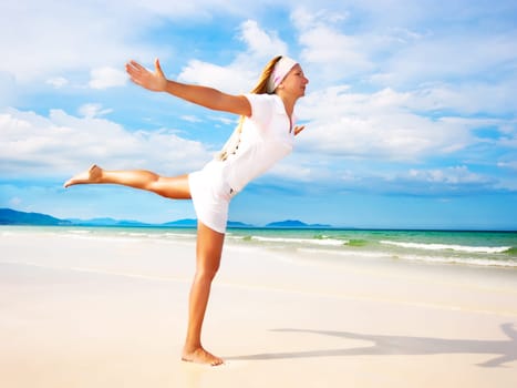 Young woman doing morning exercises close to the ocean