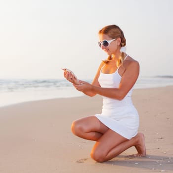 Woman with seashell on the beach at sunrise time