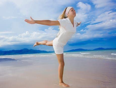 Young woman doing morning exercises close to the ocean
