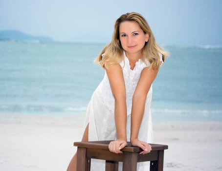 Young fashion woman posing on the white sandy beach