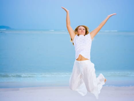 Young woman jumping on the tropical beach