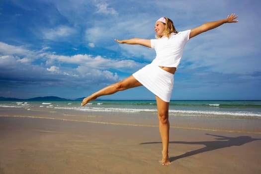 Young woman doing morning exercises close to the ocean