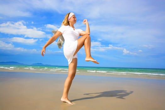 Young woman doing morning exercises close to the ocean