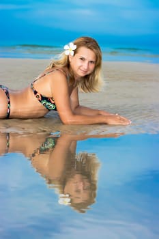 Reflection of Young woman with plimeria flower on the tropical beach.