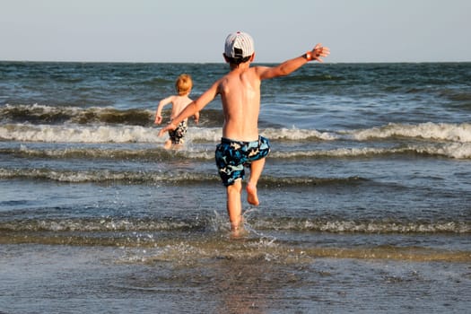 Boys running into the sea