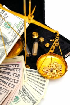 Gold nuggets in the pan of a balance scale with many fifty and hundred dollar bills showing the value of both