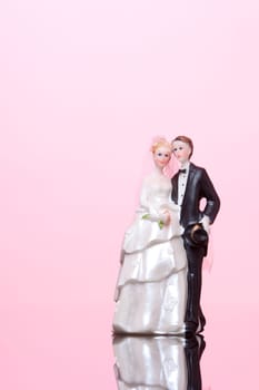 Wedding figurines (bride and groom) on pink background.