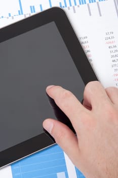 Modern business analyst working with digital tablet computer, sheet and graphs. Vertical composition, top view.