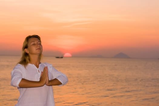 Young woman doing yoga exercises at sunrise time