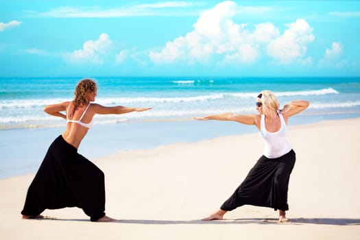 Two beautiful young woman training near the ocean