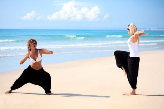 Two beautiful young woman training near the ocean