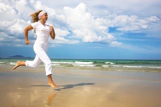 Young woman is running near the ocean. Space for copy