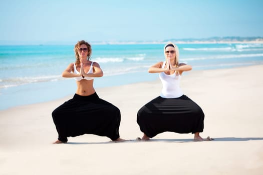 Two young beautiful woman in cambodian pants doing yoga exercises