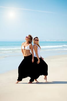 Two young beautiful woman in cambodian pants near the ocean