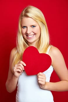 Young blonde woman with red heart in hands