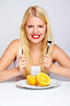 Happy young woman eating fruit with cutlery