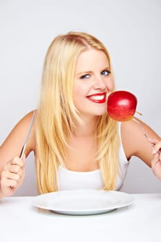 Happy young woman eating fruit with cutlery