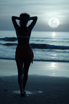 Woman on the beach under moonlight at night time