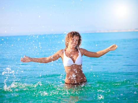 Young beautiful woman making splash of water.
