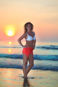 Young beautiful woman at sunrise time near the ocean