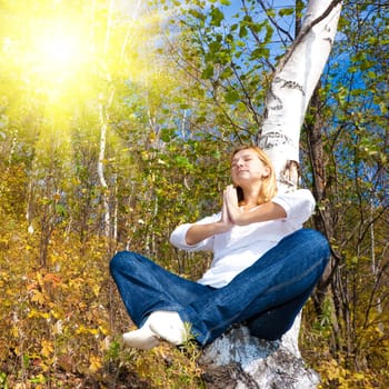 Woman meditating on the birch tree